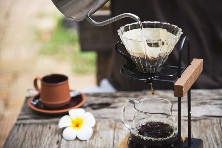 Man making drip fresh coffee in vintage coffee shop with green nature background - people with fresh coffee in nature concept
